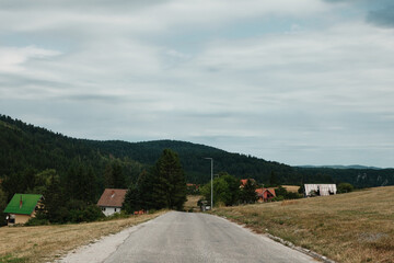 Road leading through village in Tara National Park, Serbia, with forested hills.