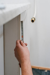 Man measure wall with measuring tape doing apartment repair. Close-up of hands holding a spirit...