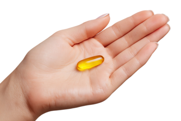 A pale hand holds a single, translucent yellow medicinal capsule