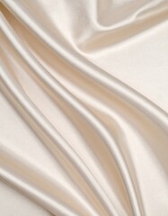 Obraz premium Smooth, flowing beige fabric with a lustrous sheen fills the frame. The material appears to be satin, characterized by its glossy finish and soft, smooth texture. 