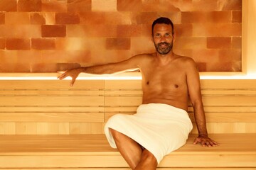 Relaxed Man Sitting in Sauna With Wooden Interior and Peaceful Atmosphere
