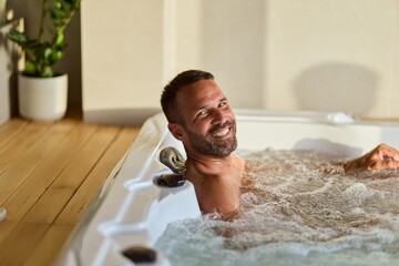 Man Relaxing in a Modern Hot Tub Indoors Smiling and Enjoying Relaxation