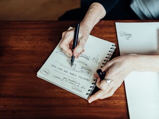 Hands writing in a notebook indoors
