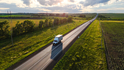 cars and trucks driving along a highway in the middle of green fields at sunset