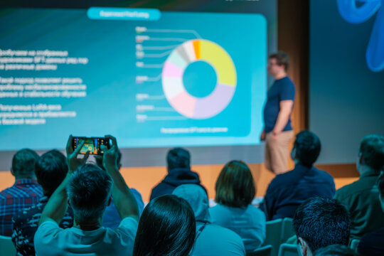 Group of people watching a business presentation featuring a graph in a conference hall