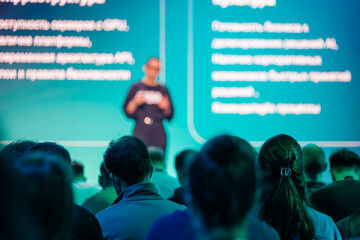Conference audience focused on speaker delivering presentation with technology-related content on...