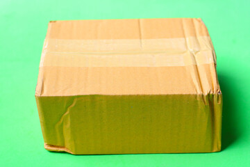 Sealed cardboard box with brown packing tape on a green background.