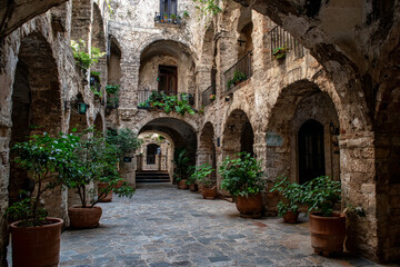 Fototapeta premium Stone courtyard with arched walkways, potted plants