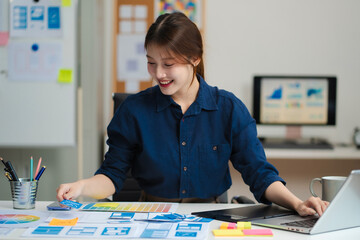 Female coder or developer working using a computer display and smartphone in problem solving at workplace.