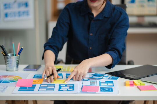 Female coder or developer working using a computer display and smartphone in problem solving at workplace.