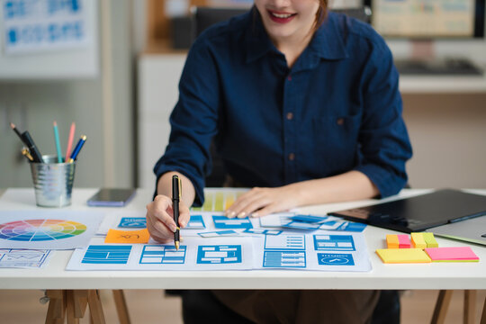 Female coder or developer working using a computer display and smartphone in problem solving at workplace.