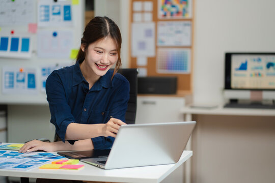 Female coder or developer working using a computer display and smartphone in problem solving at workplace.