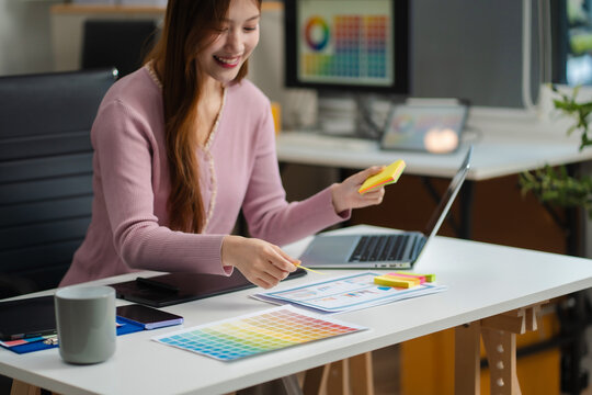 Female coder or developer working using a computer display and smartphone in problem solving at workplace.