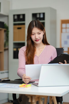 Female coder or developer working using a computer display and smartphone in problem solving at workplace.