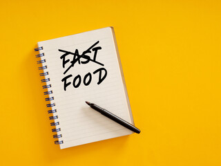 Notepad with crossed out fast food writing and pen on yellow background