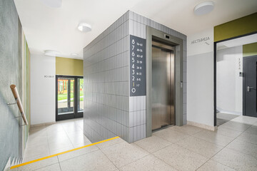 Modern elevator area in a well-lit building with clear signage and stylish design elements