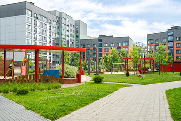 Playground area in modern residential community featuring green space and colorful play equipment during daytime