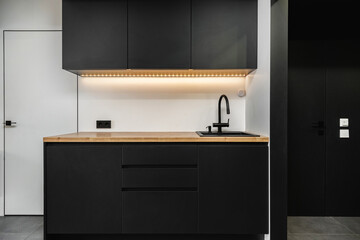 Modern black kitchen with minimalist design and wooden countertop showcasing contemporary elegance and functionality