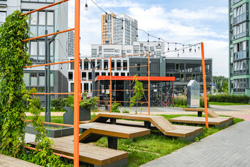 Urban park area with modern architecture, greenery, and seating in a city environment during daylight © валентин Орсик