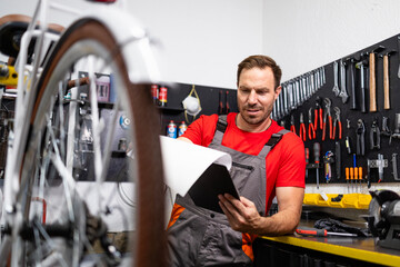 Bicycle mechanic checking service history in papers. Bike workshop.