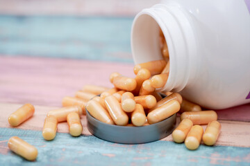 Capsules spilled from a container on a colorful background in a bright setting
