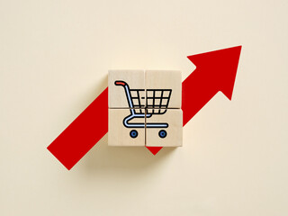 Shopping cart icon on wooden blocks and rising red arrow representing increasing sales