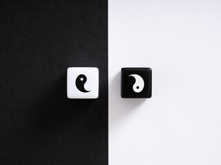 Yin and yang symbol on two wooden blocks over black and white background representing opposing and complementary forces