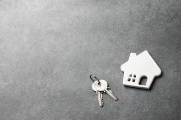 A white house model with keys on a stone background. Top view, flat lay.