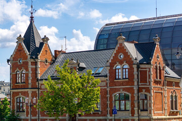 Historic red brick building in Bydgoszcz with a modern glass structure in the background.