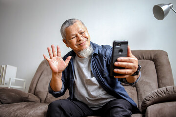 Elderly Man Waving Hands While Video Call Using Phone At Home
