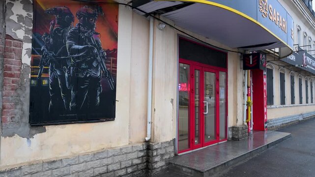A shop selling military gear in wartime Kharkiv, Ukraine. A large image of soldiers on the building's facade highlights how the conflict has become part of the city's daily life