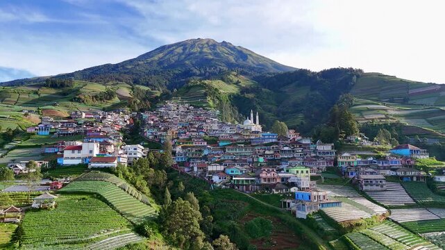 Aerial captivating highland view, showing a densely built village on a green mountain slope. Nepal Van Java village, Mount Sumbing, Indonesia.