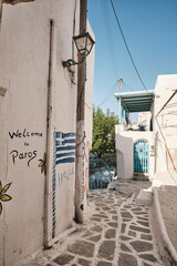 Benvenuti a Paros: vicolo tipico con murales e bandiera greca nell&rsquo;isola delle Cicladi, in verticale