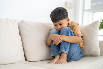 Young boy sitting with thoughtful expression, child feeling emotional sadness and sorrow, melancholic mood, childhood emotions, feeling lonely, introspection and reflection, grief and solitude