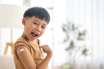 Asian boy strong pose with a raised fist after vaccination with bandage on arm, child health care,...