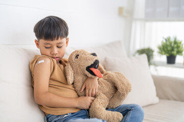 Portrait of happy smile vaccinated little asian kid boy children ages 5 to 11 years old posing show arm with medical plaster after Injection vaccine Covid-19 protection.coronavirus vaccination kid