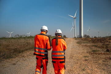 Rear view male and female wind turbine engineers working in windmill environment power plant