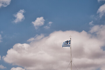 Bandiera greca che sventola al vento su cielo azzurro: simbolo di orgoglio nazionale.