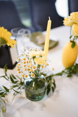 Festive table decor in yellow and white tones with flowers and lemons.