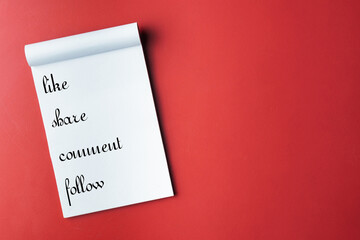 Notepad with Social Media Engagement Commands on a Bright Red Background