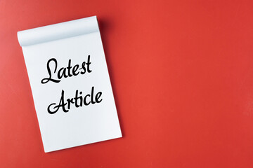 Notepad on a Red Background with 'Latest Article' Text Displayed