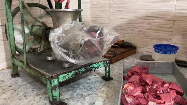 A butcher is making a minced meat in a butcher shop.