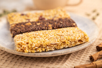 granola bars with caramel, nuts, flakes in ceramic plate on brown concrete. Side view, selective focus.
