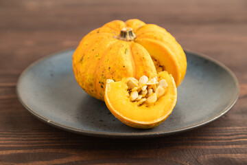 Orange Pumpkin cutted on blue plate on brown wooden. Side view, copy space