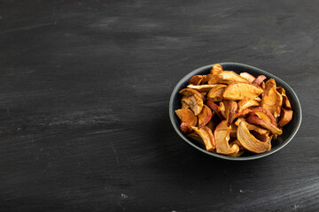 Dried Apples in ceramic bowl on black wooden. Side view, copy space