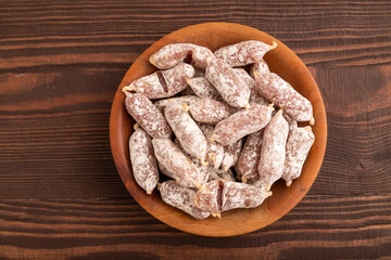 Small smoked Chicken sausages in wooden bowl on brown wooden. close up, copy space
