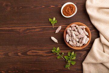 Small smoked Chicken sausages in wooden bowl on brown wooden. top view, flat lay, copy space