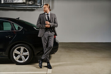 A stylish businessman with a beard exudes confidence beside his luxury car in the garage.