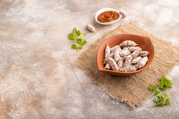 Small smoked Chicken sausages in clay bowl on brown concrete. side view, copy space