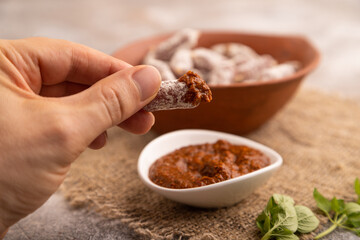 Small smoked Chicken sausages in clay bowl with hand on brown concrete. side view, close up, selective focus
